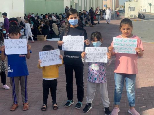 Afghan children hold banners during a protest over lenghty U.S. relocation process, at a Gulf facility where they have been housed since fleeing their homeland last year, in Abu Dhabi, United Arab Emirates, February 10, 2022 in this picture obtained from social media. Rise to Peace/via REUTERS