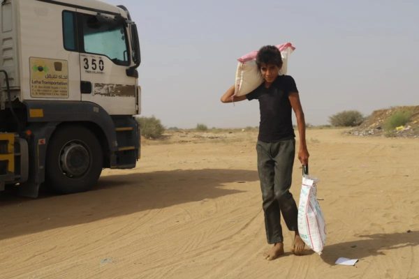 A child carries aid supplies in Yemen [Mohammed Al Wafi - Anadolu Agency]
