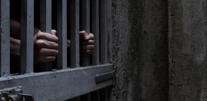 Prisoner's hands behind bars